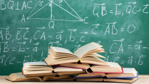 stack of books infront of blackboard