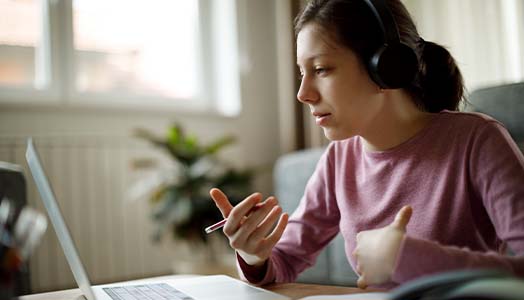 A student studying at home on a laptop with headphones on