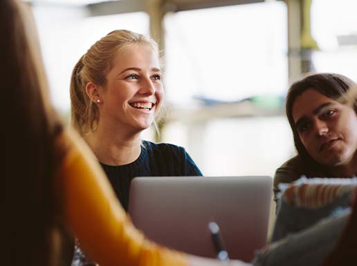 Photo of student smiling whilst working on a laptop