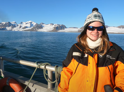 woman standing on boat with snow capped land in background