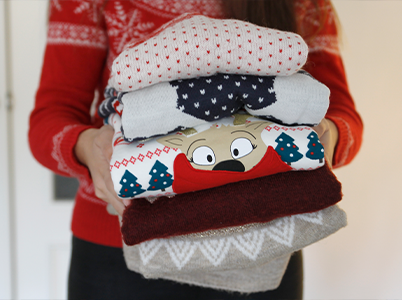 woman holding stack of christmas jumpers