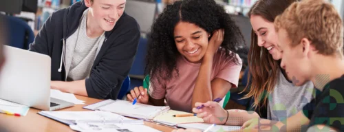 Group Of College Students Collaborating On Project In Library
