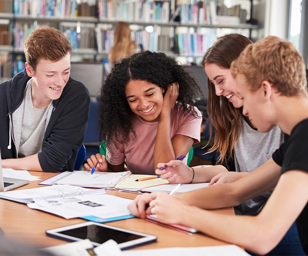 Group Of College Students Collaborating On Project In Library
