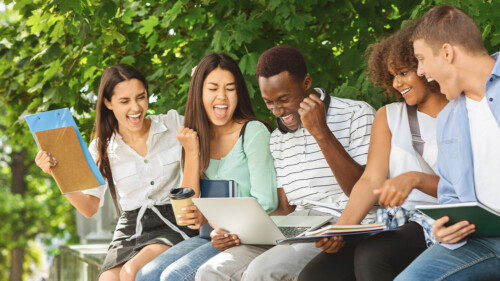 A group off happy students celebrating success outdoors, checking their test scores